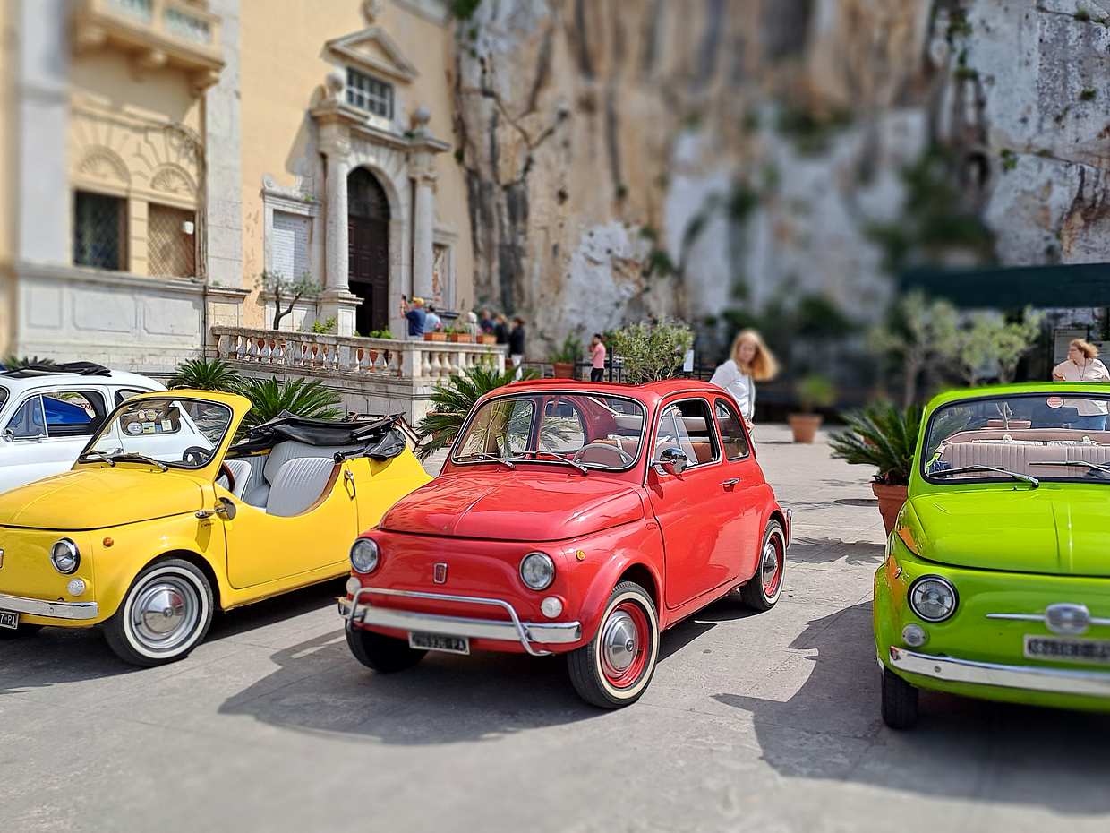 An iconic vintage Fiat 500 driving around Palermo in Italy